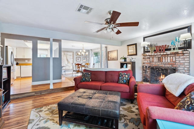 living area with a chandelier, wood finished floors, ceiling fan, a fireplace, and baseboards