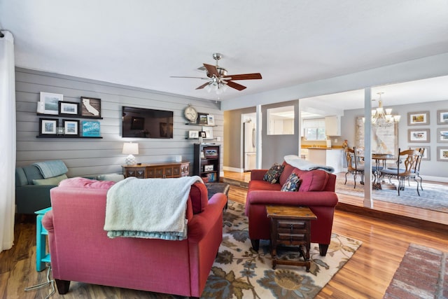 living area featuring wood finished floors, a chandelier, and a ceiling fan
