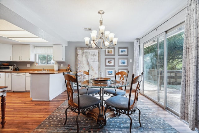 dining area with light wood finished floors and a chandelier