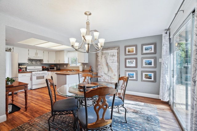 dining area featuring a chandelier, wood finished floors, and baseboards