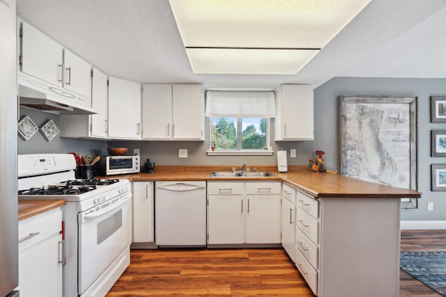 kitchen with white appliances, under cabinet range hood, a sink, a peninsula, and dark wood-style flooring