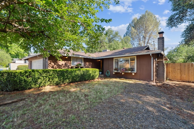 ranch-style home featuring a chimney, fence, and an attached garage