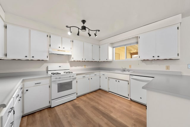 kitchen featuring white appliances, under cabinet range hood, a sink, light wood-type flooring, and white cabinetry
