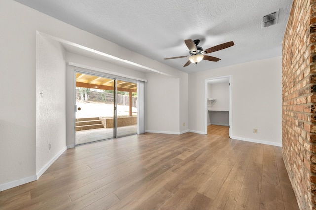 unfurnished room featuring ceiling fan, hardwood / wood-style flooring, baseboards, and a textured ceiling