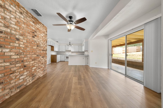 unfurnished living room featuring brick wall, ceiling fan, and light wood-style floors