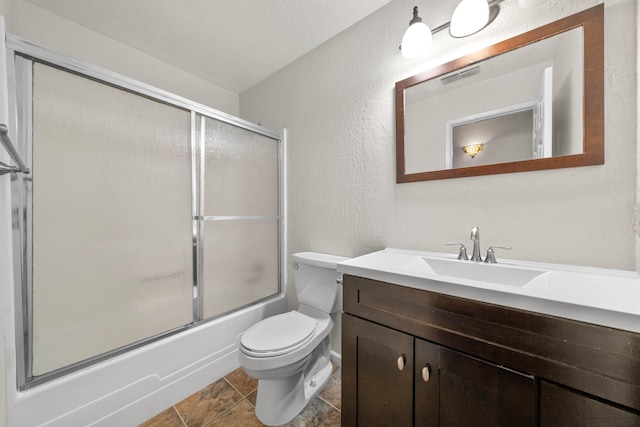 full bath featuring a textured wall, toilet, vanity, and enclosed tub / shower combo