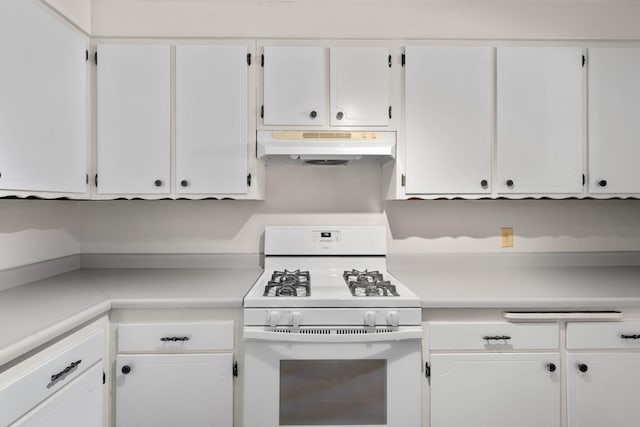 kitchen with under cabinet range hood, white gas range oven, white cabinets, and light countertops