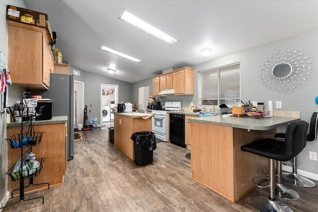 16605 Lassen Ave, Anderson, CA 96007 - kitchen with white range with gas cooktop, washer / clothes dryer, black dishwasher, a peninsula, and a center island