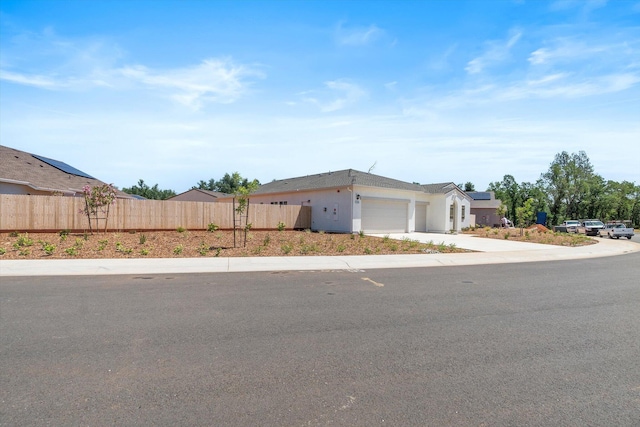 5555 Feathers Ave, Redding, CA 96002 - ranch-style home with fence, a garage, concrete driveway, solar panels, and stucco siding