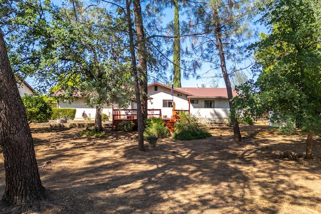 rear view of house with a wooden deck and stucco siding
