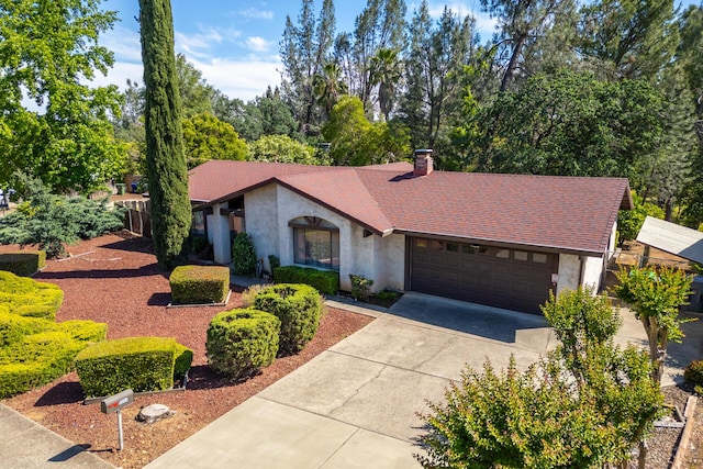 mid-century modern home featuring an attached garage, a chimney, concrete driveway, and stucco siding