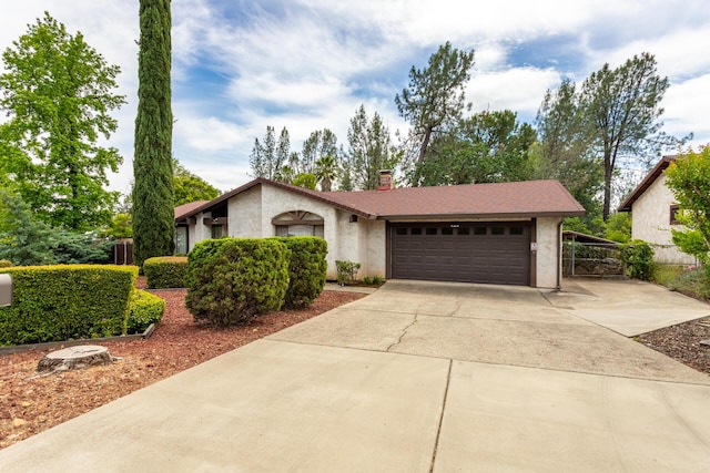 mid-century home with driveway, an attached garage, stucco siding, and a chimney