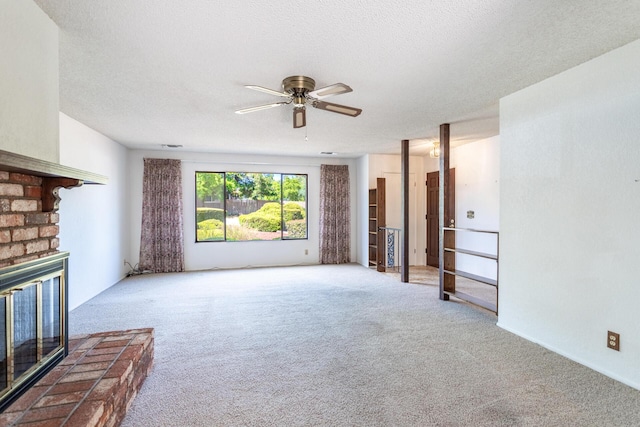 unfurnished living room featuring carpet, ceiling fan, a brick fireplace, and a textured ceiling