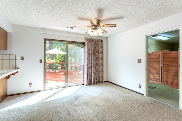 unfurnished living room featuring carpet flooring, a ceiling fan, baseboards, and a textured ceiling