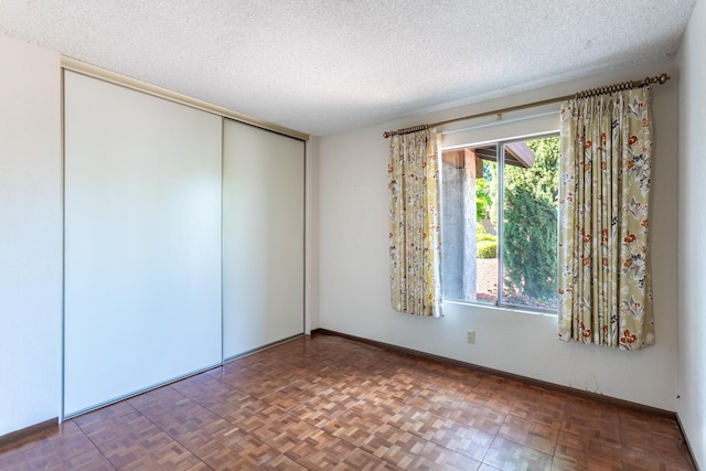 empty room featuring a textured ceiling and baseboards