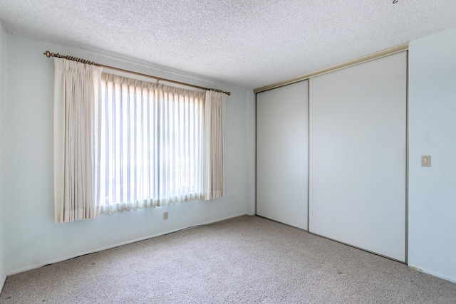 carpeted empty room featuring a textured ceiling