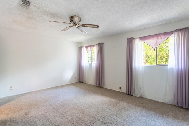 carpeted spare room with a ceiling fan and a textured ceiling