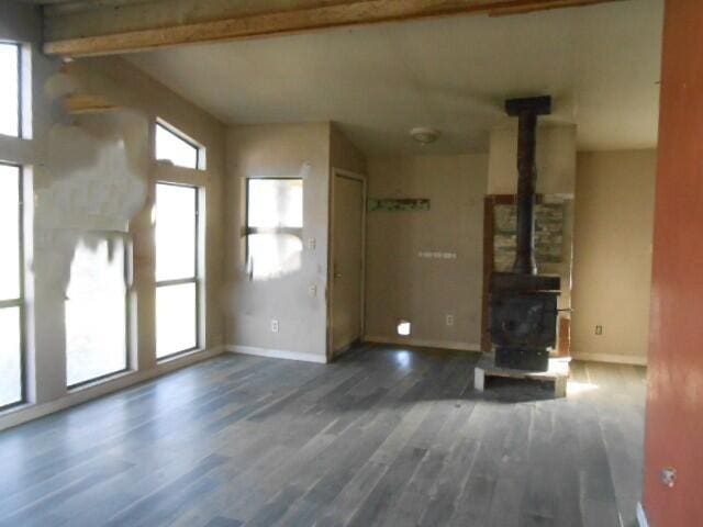 1090 Crooked Oak Ln, Redding, CA 96003 - unfurnished living room with a wood stove, healthy amount of natural light, wood finished floors, baseboards, and beam ceiling