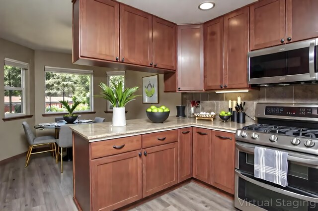 7289 Clarabelle Ln, Shingletown, CA 96088 - kitchen featuring appliances with stainless steel finishes, light wood-style flooring, a peninsula, brown cabinets, and light stone countertops