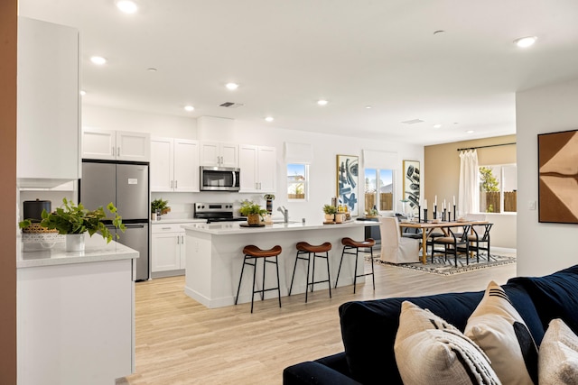 4148 Haleakala Ave, Redding, CA 96001 - kitchen with stainless steel appliances, open floor plan, a breakfast bar, white cabinets, and recessed lighting