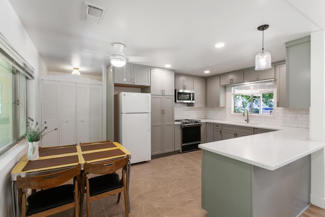 2722 Russell St, Redding, CA 96001 - kitchen featuring freestanding refrigerator, stainless steel microwave, gray cabinetry, a sink, and range with gas stovetop