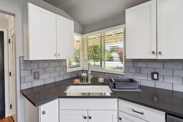 5801 Mountain View Dr, Redding, CA 96003 - kitchen featuring a sink, decorative backsplash, dark countertops, vaulted ceiling, and white cabinets