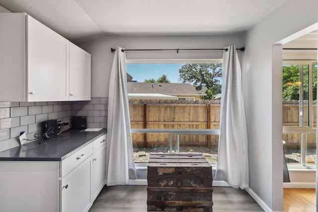 5801 Mountain View Dr, Redding, CA 96003 - kitchen with dark countertops, decorative backsplash, white cabinets, light wood finished floors, and lofted ceiling
