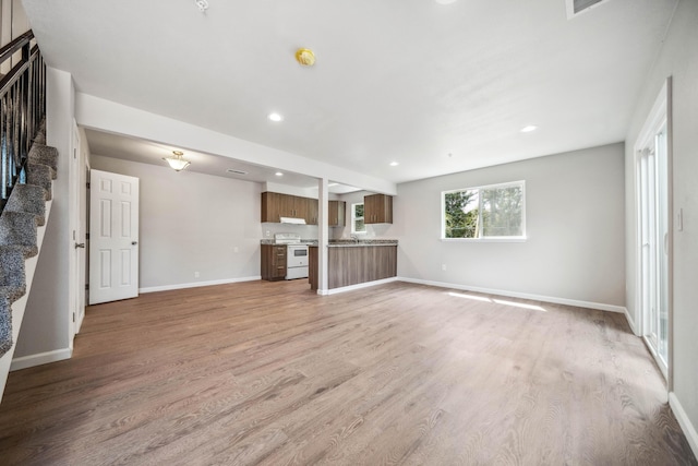 628 Hartnell Ave, Redding, CA 96002 - unfurnished living room with stairs, light wood-style flooring, baseboards, recessed lighting, and a sink