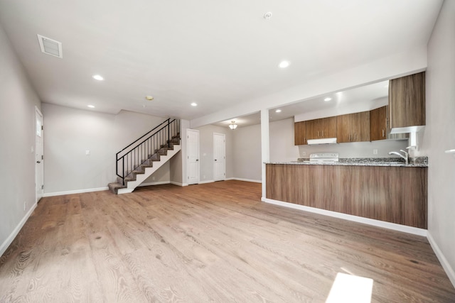628 Hartnell Ave, Redding, CA 96002 - kitchen with brown cabinets, under cabinet range hood, light stone counters, recessed lighting, and light wood-style floors