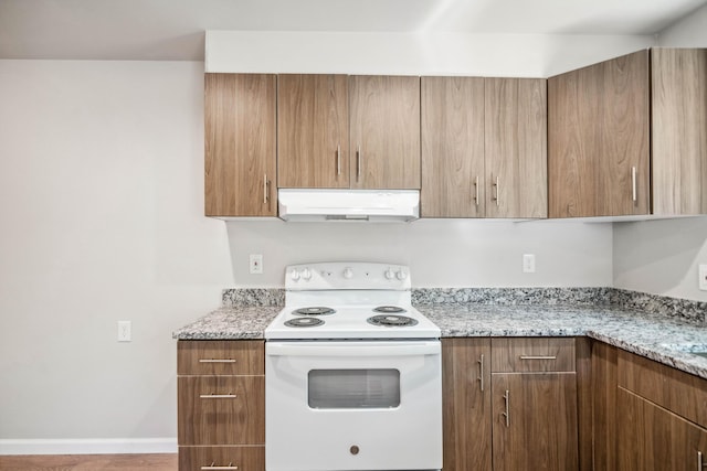 628 Hartnell Ave, Redding, CA 96002 - kitchen with under cabinet range hood, white electric range oven, light stone counters, brown cabinets, and baseboards