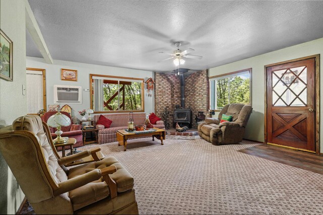7372 Tahoe Ln, Shingletown, CA 96088 - carpeted living room featuring a wood stove, a textured ceiling, ceiling fan, and a wall unit AC
