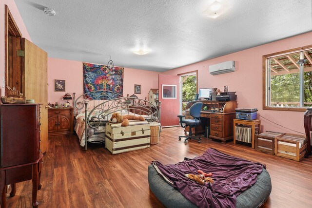 7372 Tahoe Ln, Shingletown, CA 96088 - bedroom with an AC wall unit, wood finished floors, multiple windows, and a textured ceiling