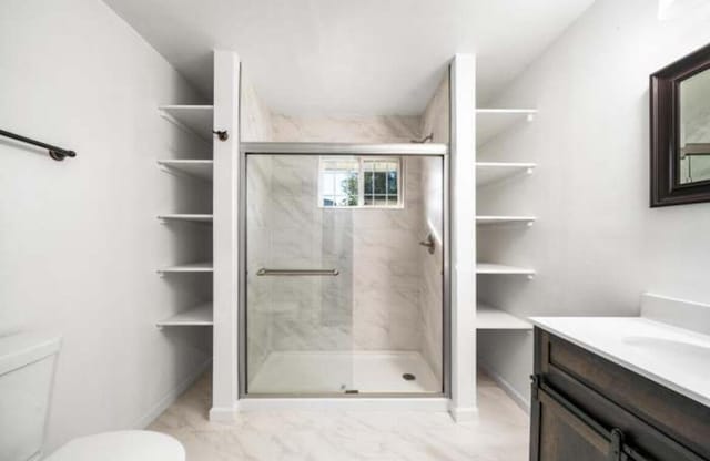 1640 Wisconsin Ave, Redding, CA 96001 - full bathroom with a shower stall, toilet, marble finish floors, vanity, and baseboards
