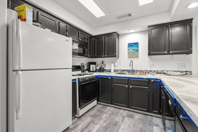 910 Montcrest Dr, Redding, CA 96003 - kitchen with freestanding refrigerator, gas range, black microwave, a sink, and light wood-type flooring