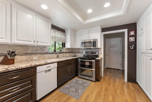 6766 Drake Dr, Anderson, CA 96007 - kitchen featuring appliances with stainless steel finishes, white cabinetry, tasteful backsplash, a raised ceiling, and light wood-style floors