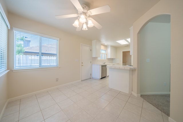 2184 Darsha Ln, Redding, CA 96003 - kitchen with stainless steel dishwasher, tile countertops, white cabinetry, light tile patterned flooring, and baseboards
