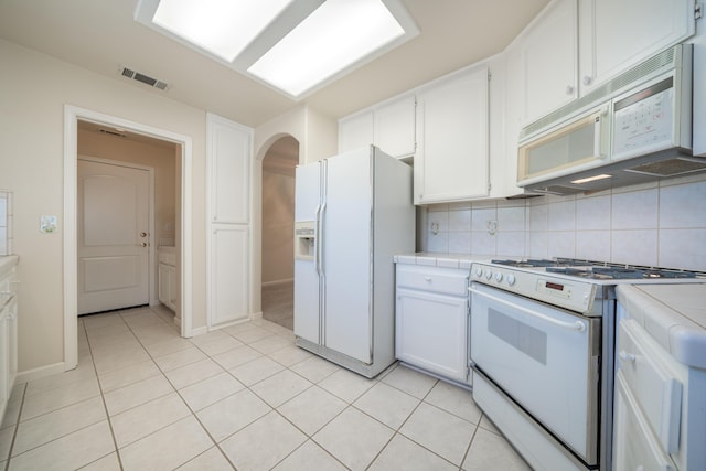 2184 Darsha Ln, Redding, CA 96003 - kitchen featuring white appliances, tile counters, arched walkways, white cabinets, and light tile patterned floors