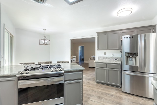 10844 Green Oaks Ln, Redding, CA 96003 - kitchen featuring stainless steel appliances, gray cabinetry, light wood-type flooring, a chandelier, and light stone counters