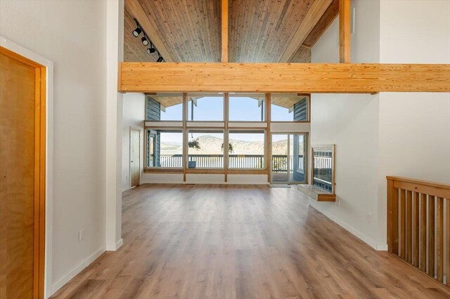 4740 Rainbow, Weed, CA 96094 - unfurnished living room featuring plenty of natural light, a high ceiling, track lighting, baseboards, and wood ceiling with exposed beams