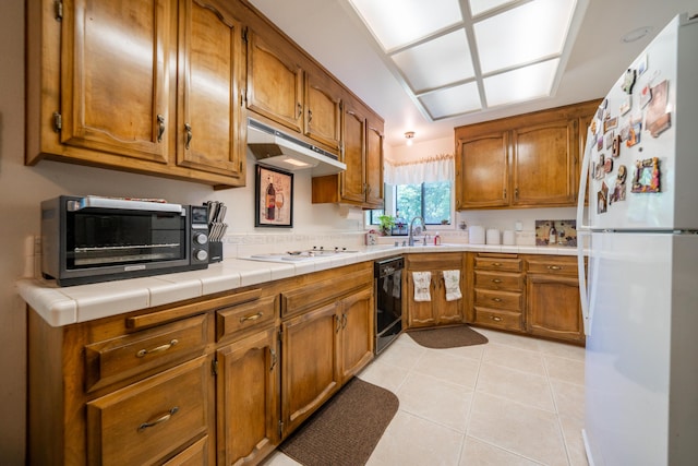 19991 Paso Robles Ave, Redding, CA 96003 - kitchen with white appliances, brown cabinetry, under cabinet range hood, light tile patterned floors, and a sink