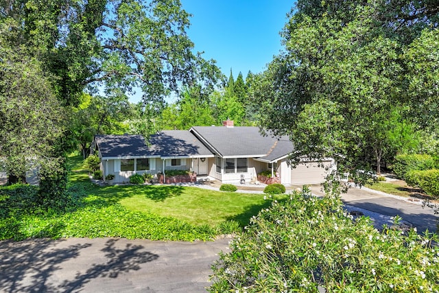 19991 Paso Robles Ave, Redding, CA 96003 - ranch-style house with concrete driveway, a porch, an attached garage, a front lawn, and a chimney