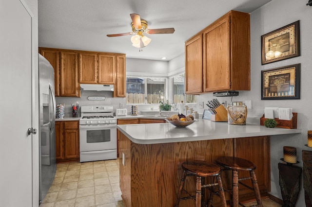 3608 Capricorn Way, Redding, CA 96002 - kitchen with gas range gas stove, a peninsula, stainless steel refrigerator with ice dispenser, under cabinet range hood, and brown cabinets