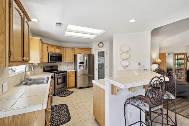 2654 Queens Way, Redding, CA 96001 - kitchen with stainless steel appliances, a sink, a peninsula, tile countertops, and a kitchen breakfast bar