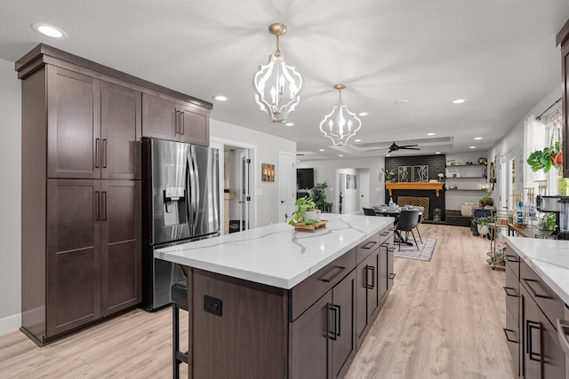 4223 Alta Mesa Dr, Redding, CA 96002 - kitchen with stainless steel refrigerator with ice dispenser, a chandelier, light wood finished floors, a fireplace, and dark brown cabinetry
