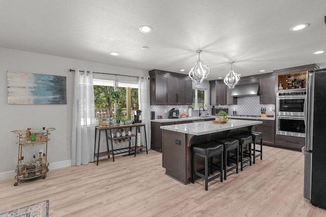 4223 Alta Mesa Dr, Redding, CA 96002 - kitchen with wall chimney exhaust hood, a sink, stainless steel appliances, dark brown cabinets, and a chandelier