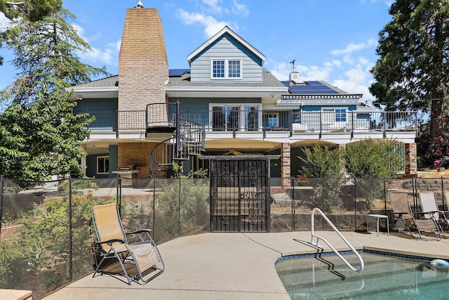 3330 Scenic Dr, Redding, CA 96001 - rear view of house with a balcony, roof mounted solar panels, a shingled roof, a gate, and a patio area