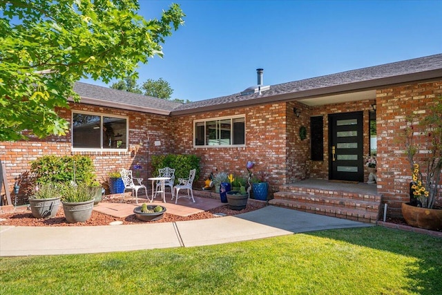 21350 Wilcox Rd, Red Bluff, CA 96080 - doorway to property featuring brick siding, a yard, a shingled roof, and a patio area