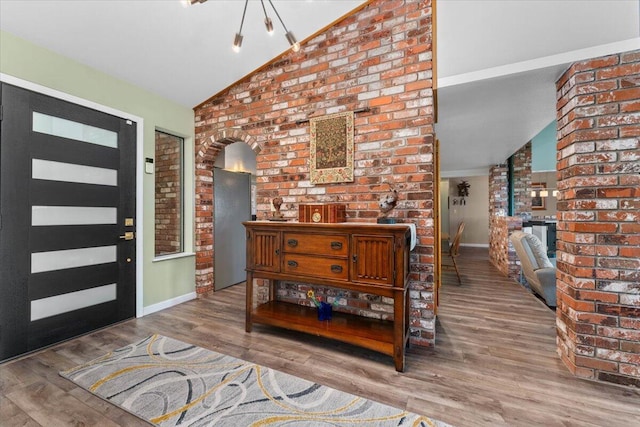 21350 Wilcox Rd, Red Bluff, CA 96080 - foyer with lofted ceiling, arched walkways, baseboards, wood finished floors, and brick wall