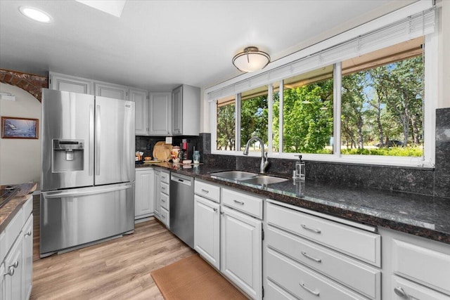 21350 Wilcox Rd, Red Bluff, CA 96080 - kitchen featuring appliances with stainless steel finishes, a sink, tasteful backsplash, light wood-style flooring, and dark stone counters