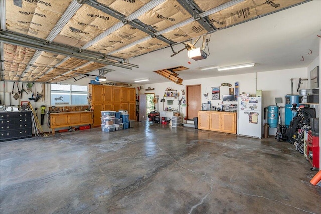 21350 Wilcox Rd, Red Bluff, CA 96080 - garage with freestanding refrigerator, a workshop area, and a garage door opener
